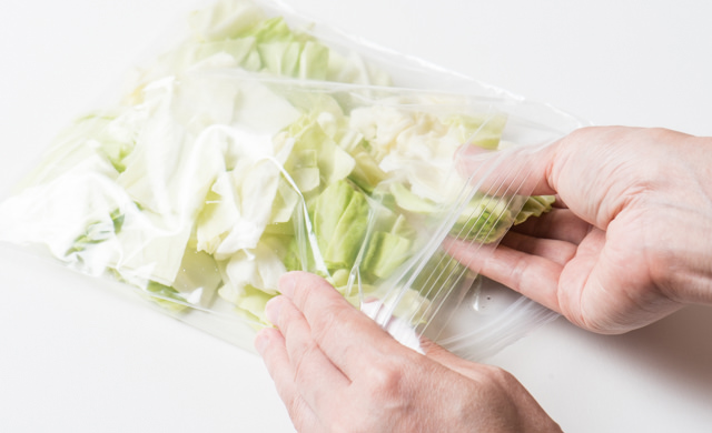 冷凍用保存袋にキャベツを平らに入れている写真