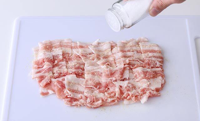 切った豚バラ肉に塩を振っている写真