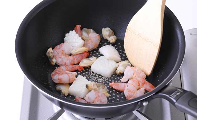 フライパンでシーフードミックスを炒めている写真