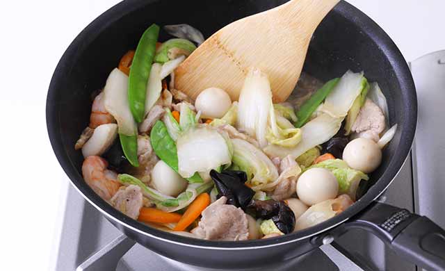 すべての具材が入ったフライパンに水溶き片栗粉を加えて混ぜている写真