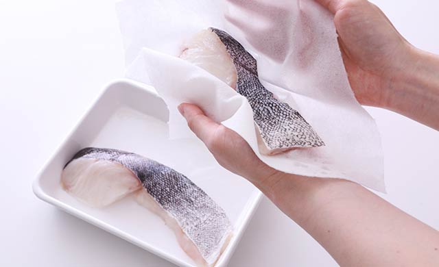 たらの水分をキッチンペーパーで拭き取っている写真