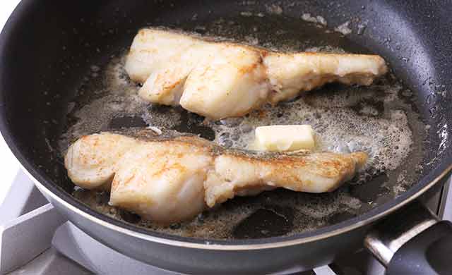 バターを絡めながら、たらを焼いている写真